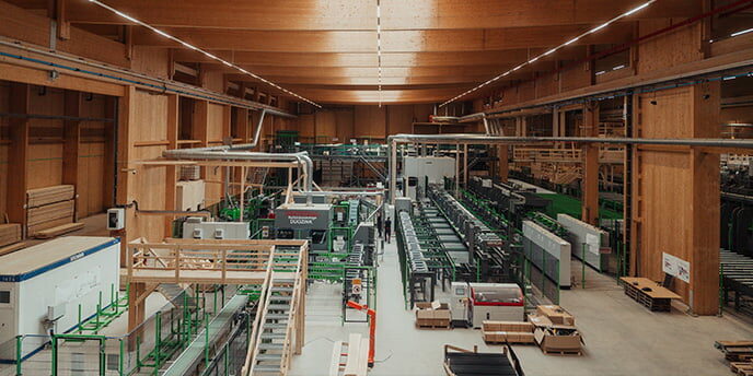 Fabrikhalle mit hochmodernen Maschinen und Holzverarbeitungsanlagen in einem großen, holzverkleideten Gebäude.